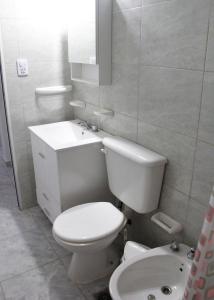 Baño blanco con aseo y lavamanos en ALOJAMIENTO SARMIENTO en General Alvear