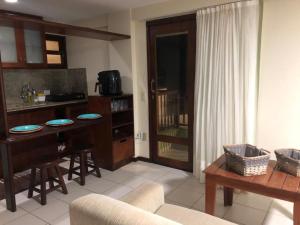 ein Wohnzimmer mit einem Tisch und einer Küche in der Unterkunft Flat completo a beira mar com vista exuberante no Blue Marlin Apartments in Natal