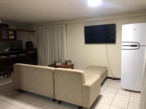 ein Wohnzimmer mit einem Sofa und einem Flachbild-TV in der Unterkunft Flat completo a beira mar com vista exuberante no Blue Marlin Apartments in Natal