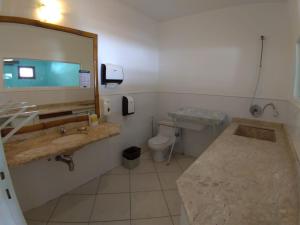 a bathroom with a sink and a toilet and a mirror at Rio Búzios Beach Hotel in Búzios