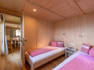 a bedroom with two beds in a room with wooden walls at Biobauernhof Fleckl in Hopfgarten im Brixental