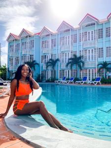 a woman sitting on a surfboard next to a swimming pool at Bay Gardens Marina Haven in Gros Islet