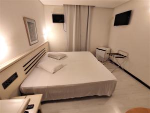 ein Schlafzimmer mit einem weißen Bett in einem Zimmer in der Unterkunft Granville Hotel in Curitiba
