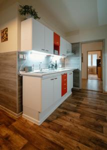 una cocina con armarios blancos y rojos y suelos de madera. en Apartmán Dobré ráno, en Banská Štiavnica