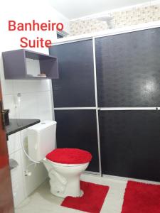 a bathroom with a toilet with a red rug at Bangalôs Riviera do Atlantico in Jacumã