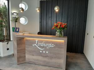 a reception desk with a vase of flowers on it at Hotel Limburgia in Kanne