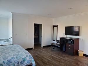 a hotel room with a bed and a flat screen tv at Ocean Surf Inn & Suites in Huntington Beach