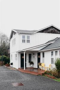 a white house with a porch with two chairs at Boardwalk Cottages in Long Beach