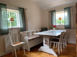 uma sala de estar com uma mesa, cadeiras e janelas em Källåsens Stuguthyrning em Sjötofta