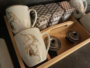 due tazze da caffè in un vassoio di legno con una scatola di Gîtes Spa en Baie de Somme a Grand-Laviers
