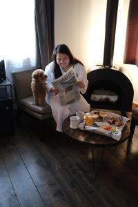 Eine Frau, die auf einer Couch sitzt und mit einem Hund eine Zeitung liest. in der Unterkunft Ashore Hotel in Seaside