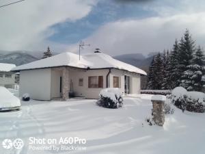 a house covered in snow with trees and mountains at Chalet Katy in Kupres