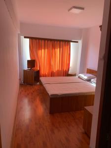 een slaapkamer met een bed en een raam met een oranje gordijn bij HOTEL modern / Imobiliare Garcea Titu in Titu