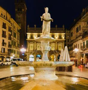 Una statua di una donna seduta sopra una fontana di Casa Martini Piazza Erbe a Verona