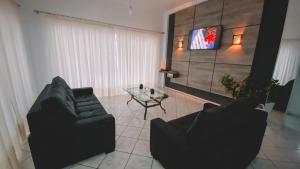a living room with two couches and a tv at Nacional Park Hotel Lages in Lages