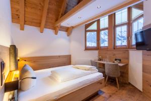 Schlafzimmer mit einem Bett, einem Schreibtisch und einem TV in der Unterkunft Hotel Luggi in Galtür + 37 Fotos