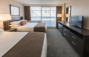 a hotel room with two beds and a flat screen tv at The Embassy Inn in Victoria