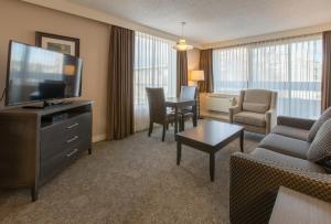 a living room with a television and a couch and a table at The Embassy Inn in Victoria +32 photos