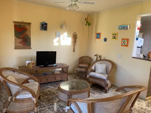 a living room with a flat screen tv and chairs at CASA NO CENTRO DE BUZIOS in Búzios