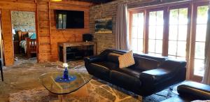 a living room with a leather couch and a glass table at Creagh Cottage and Homestead in Arrowtown