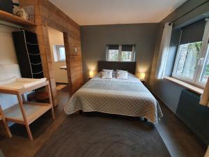 a bedroom with a bed and a table and two windows at Gite le Ravel in Hockai