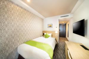 a hotel room with a bed and a flat screen tv at KOKO HOTEL Sapporo Odori in Sapporo