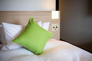 a green pillow sitting on top of a bed at KOKO HOTEL Sapporo Odori in Sapporo