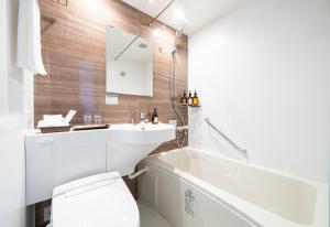 a bathroom with a toilet and a sink and a tub at KOKO HOTEL Sapporo Odori in Sapporo