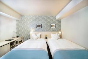 a hotel room with two beds and a desk at KOKO HOTEL Sapporo Odori in Sapporo