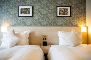 two beds in a hotel room with white pillows at KOKO HOTEL Sapporo Odori in Sapporo