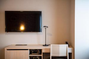 a desk with a lamp and a tv on a wall at KOKO HOTEL Sapporo Odori in Sapporo