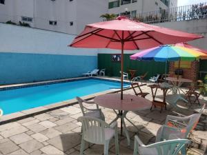 a patio with tables and umbrellas next to a pool at Regiane Beach Pousada Hostel in João Pessoa