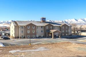 a large building in a parking lot with mountains in the background at Cobblestone Hotel & Suites - Morgan in Morgan