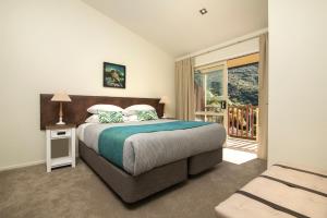 a bedroom with a bed and a balcony at Punga Cove Resort in Endeavour Inlet