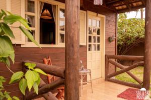une véranda dans une cabane en bois avec une table et des chaises dans l'établissement Pousada Sol & Sal Praia do Rosa, à Praia do Rosa