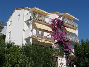 a white building with a bunch of purple flowers at Apartments Kate - 20m from the beach in Brist