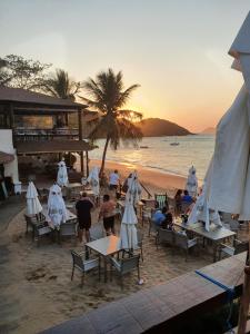 a group of people sitting on the beach at sunset at CASA COM 4 QUARTO EM BUZIOS - 2 SUITES - Perto de Tudo in Búzios