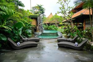 a swimming pool in a garden with benches and trees at JAPA Suites & Villas in Ubud