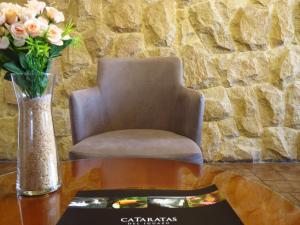 una mesa con un jarrón de flores y una silla en Casa Piedra Hotel en Villa Carlos Paz