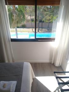 1 dormitorio con vistas a la piscina a través de una ventana en Casa Piedra Hotel en Villa Carlos Paz