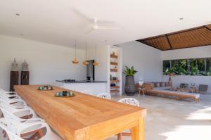a dining room with a wooden table and white chairs at Villa Passiondream including private cook & butlerservice in Jasri