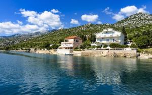 een huis aan de oever van een waterlichaam bij Apartments Domagoj - on the beach in Lukovo Šugarje