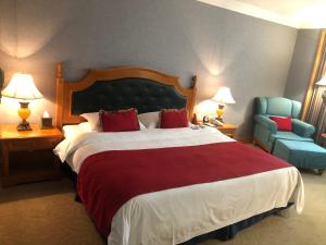una habitación de hotel con una cama grande y una silla azul en Grand Noble Hotel Dongguan, en Dongguan