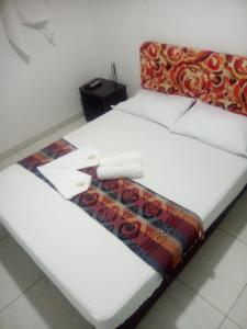 Una cama blanca con una manta encima. en montecarlos hotel, en Ibagué