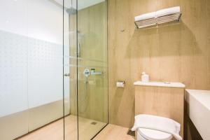 a bathroom with a toilet and a glass shower at Village Hotel Katong by Far East Hospitality in Singapore