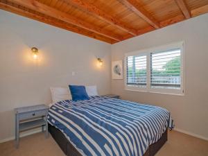 um quarto com uma cama e uma janela em Beaut Bach on Beverley - Whangamata Holiday Home em Whangamata