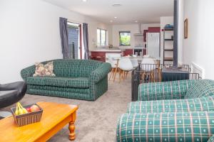 a living room with two couches and a kitchen at Hanmer All Seasons - Hanmer Springs in Hanmer Springs