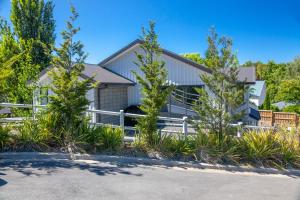 a house with a white fence and trees at Rolki House - Hanmer Springs Holiday Home in Hanmer Springs
