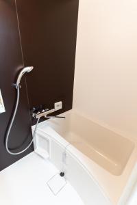 uma banheira branca com uma torneira na casa de banho em 大吉屋本館 ワンフロア貸切部屋 名駅離れ em Nagoya