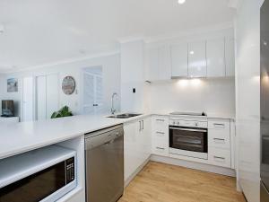 uma cozinha branca com armários brancos e um lavatório em Peurto Vallerta Unit 2 em Gold Coast